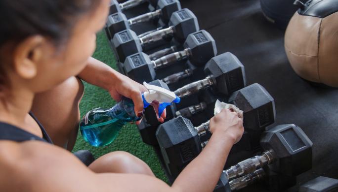 Woman cleaning gym equipment 