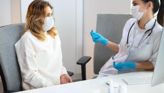 Two women in medical mask talking to each other in hospital