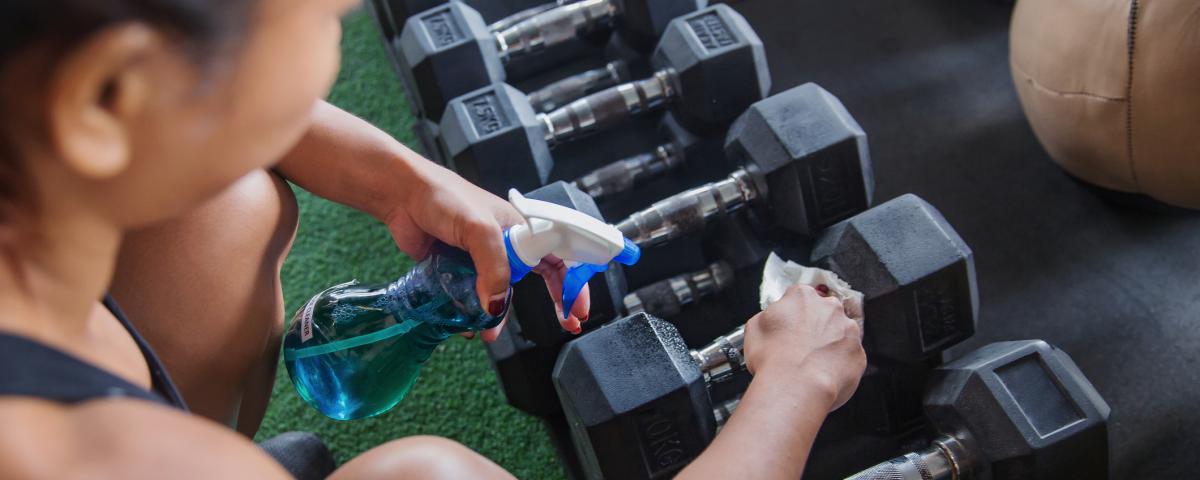 Woman cleaning gym equipment 